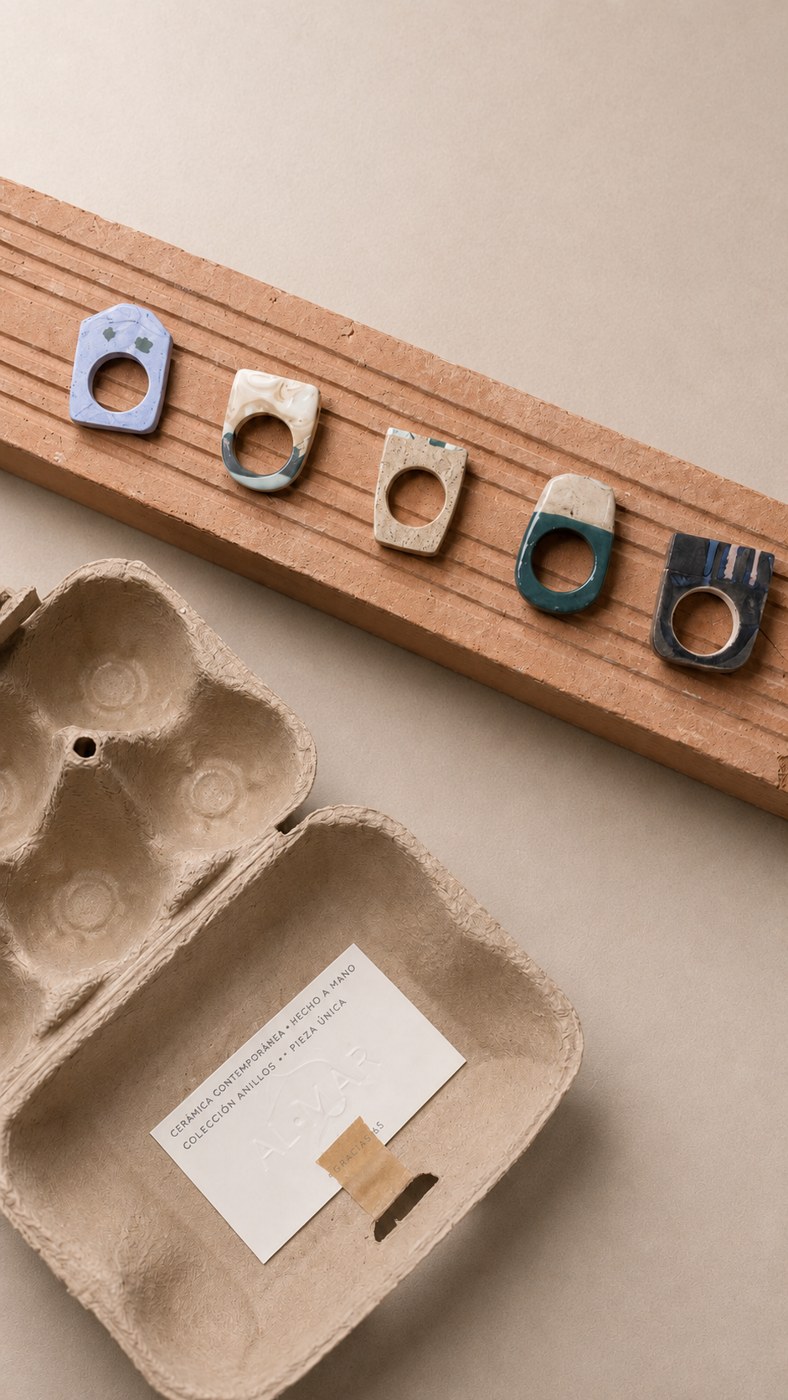 Anillos de porcelana coloreada sobre un ladrillo, junto a su caja de cartón