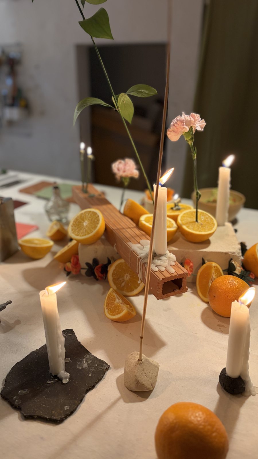 Mesa del taller de alianzas en AL MAR con velas, naranjas, claveles y ladrillos