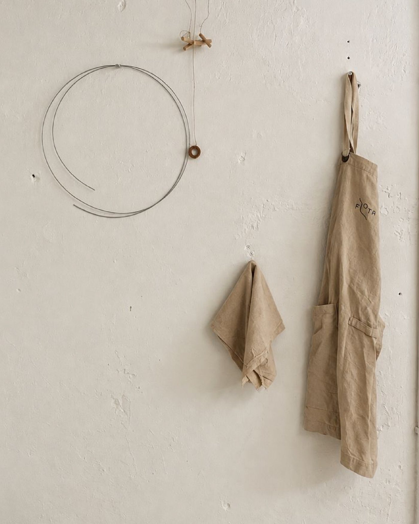 Delantal FLOTA, trapo y alambre de corte colgados en la pared del taller