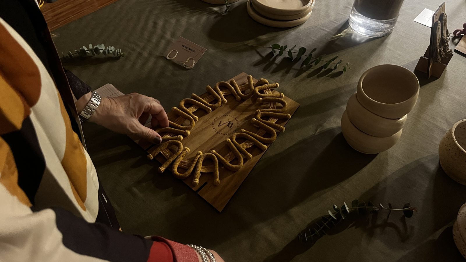 Manos acomodando una joya sobre la mesa
